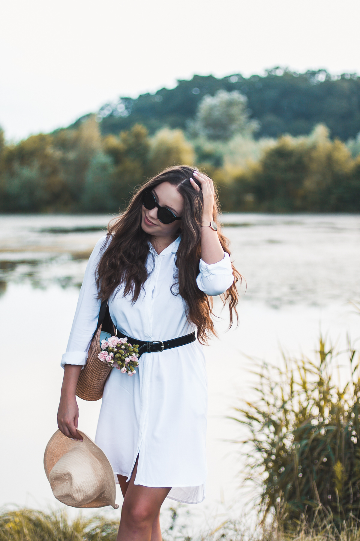 Biała sukienka w wakacyjnej stylizacji ze słomianym koszykiem